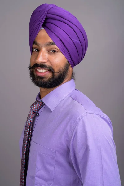 Młody przystojny biznesmen Indian Sikh sobie turban przeciwko gr — Zdjęcie stockowe