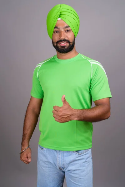 Young handsome Indian Sikh man wearing turban and green shirt — Stok fotoğraf