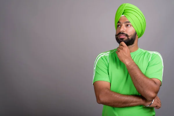 Young handsome Indian Sikh man wearing turban and green shirt — Stok fotoğraf