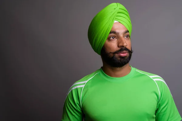 Young handsome Indian Sikh man wearing turban and green shirt — Stok fotoğraf