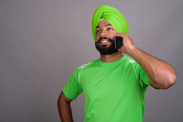 Young handsome Indian Sikh man wearing turban and green shirt — Stok fotoğraf