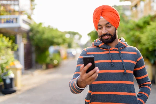 Indian Sikh man wearing using mobile phone outdoors — Stock Photo, Image