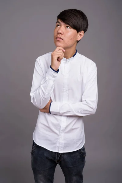 Jovem adolescente asiático contra fundo cinza — Fotografia de Stock