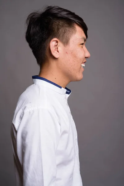 Jong aziatisch tiener jongen tegen grijs achtergrond — Stockfoto