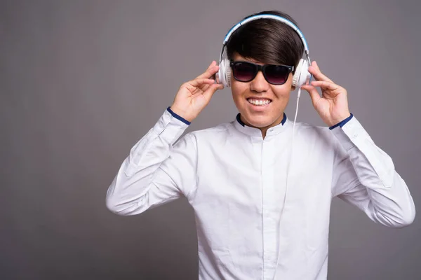 Giovane asiatico adolescente ascoltando musica contro grigio backgrou — Foto Stock