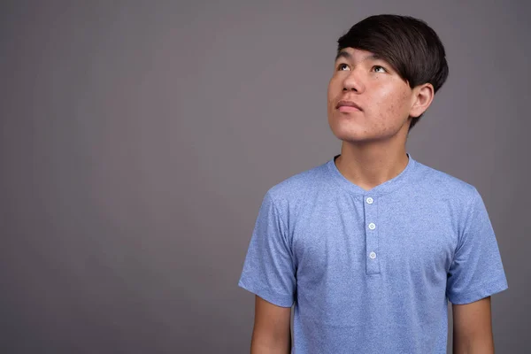 Jovem adolescente asiático contra fundo cinza — Fotografia de Stock