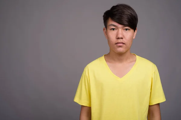 Молодой азиатский подросток на сером фоне — стоковое фото