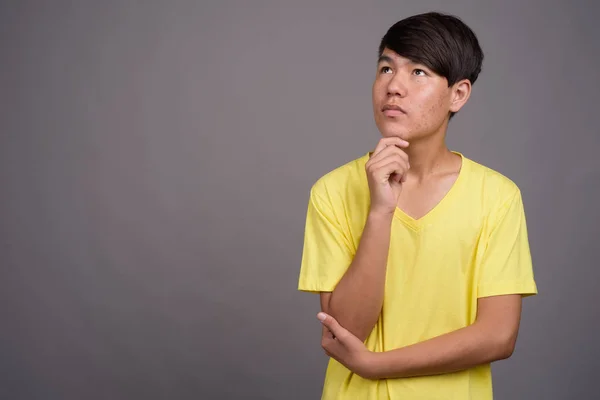Junger asiatischer Teenager vor grauem Hintergrund — Stockfoto
