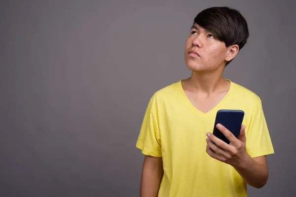 Mladý asijské dospívající chlapec proti šedé pozadí — Stock fotografie