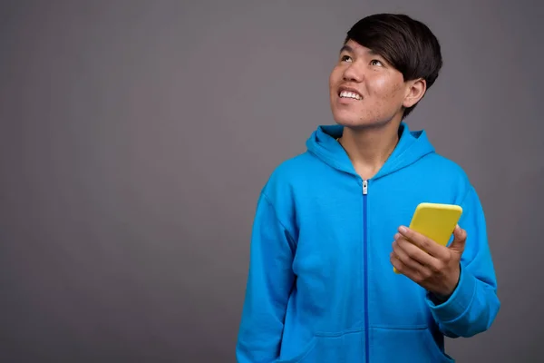 Junger asiatischer Teenager vor grauem Hintergrund — Stockfoto