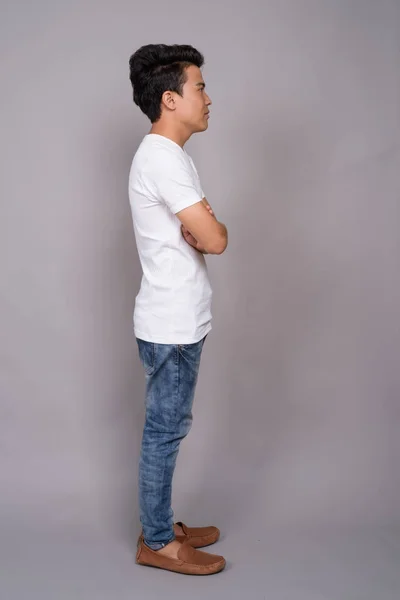 Portrait of young Asian man against gray background — Stock Photo, Image