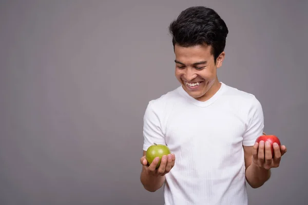 Portrait of young Asian man against gray background — Stock Photo, Image