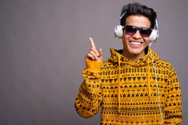 灰色の背景の下で音楽を聴く若いアジア人男性 — ストック写真