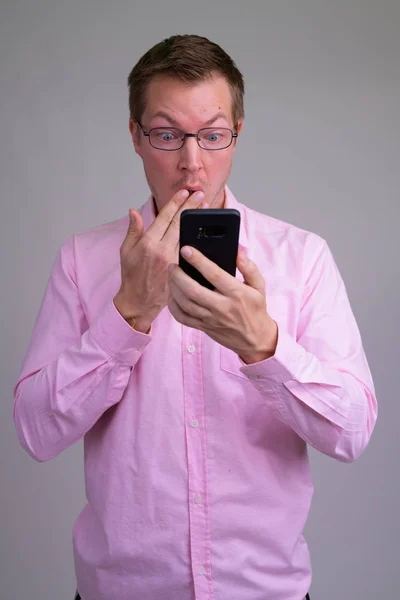 Молодий красивий бізнесмен використовує телефон і виглядає шокованим — стокове фото