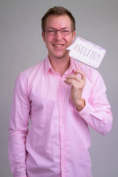 Портрет молодого счастливого бизнесмена, улыбающегося с бумажной вывеской — стоковое фото