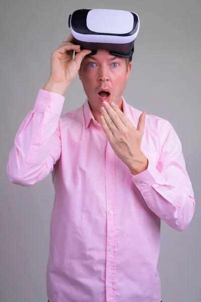 Jovem empresário bonito com fone de ouvido realidade virtual olhando chocado e surpreso — Fotografia de Stock