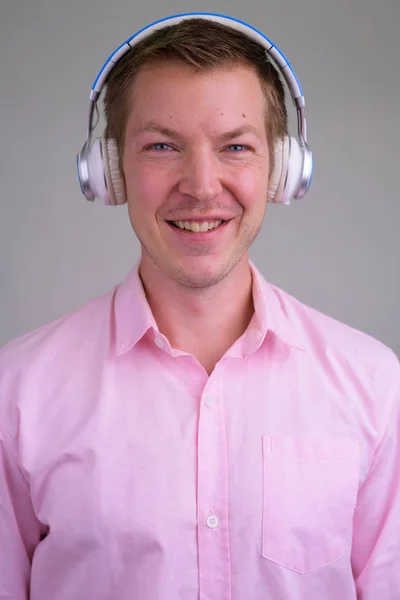 Rostro de joven empresario feliz sonriendo mientras escucha música — Foto de Stock