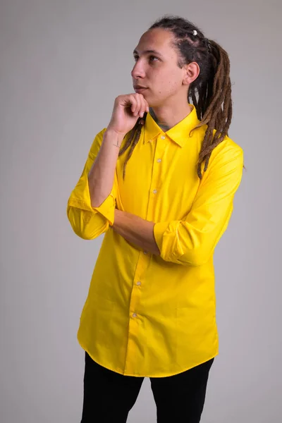 Portrait of young handsome businessman with dreadlocks thinking — Stock Photo, Image