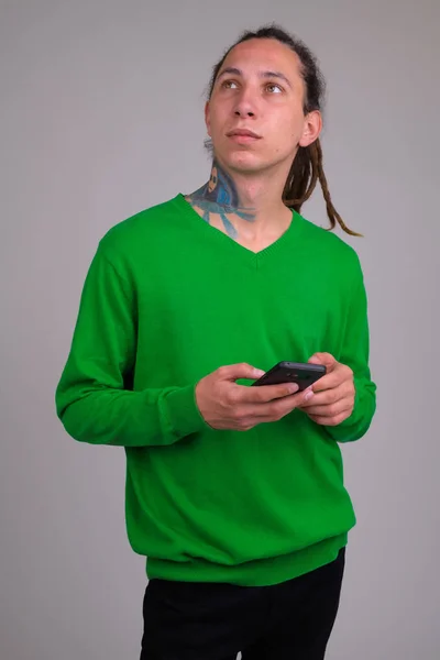 Retrato de jovem com dreadlocks pensando ao usar o telefone — Fotografia de Stock