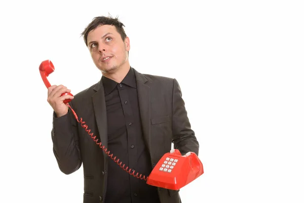 Studio shot van de Kaukasische zakenman bedrijf telefoon terwijl thi — Stockfoto