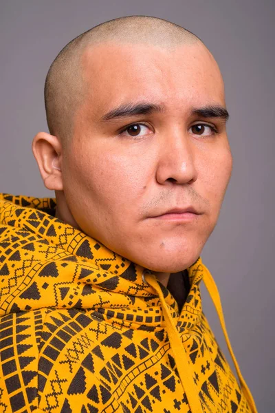 Young bald Asian man against gray background — Stock Photo, Image