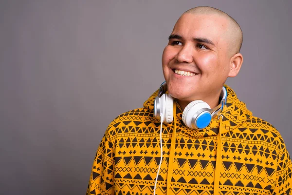 Joven calvo asiático hombre usando auriculares sobre fondo gris —  Fotos de Stock