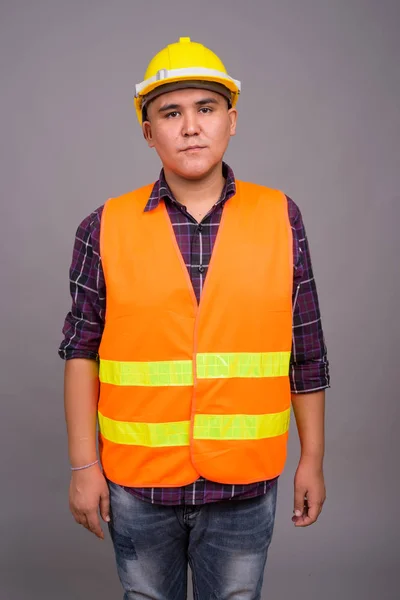 Ung asiatisk man byggnadsarbetare mot grå bakgrund — Stockfoto
