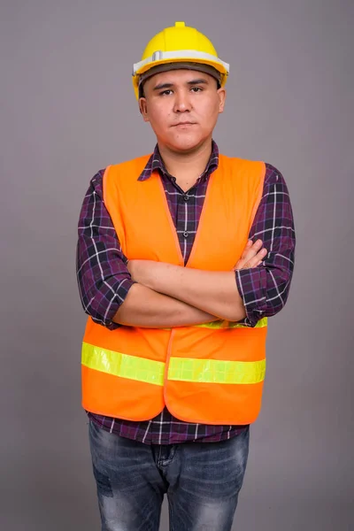 Joven asiático hombre construcción trabajador contra gris fondo — Foto de Stock