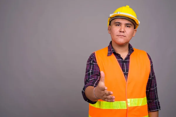 Joven asiático hombre construcción trabajador contra gris fondo —  Fotos de Stock