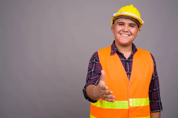 Joven asiático hombre construcción trabajador contra gris fondo — Foto de Stock