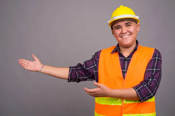Jovem ásia homem construção trabalhador contra cinza fundo — Fotografia de Stock