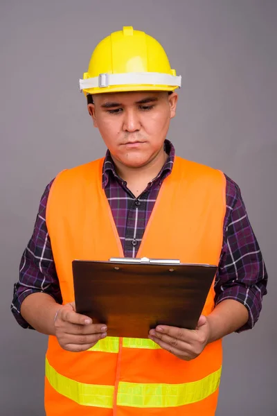 Joven asiático hombre construcción trabajador contra gris fondo —  Fotos de Stock