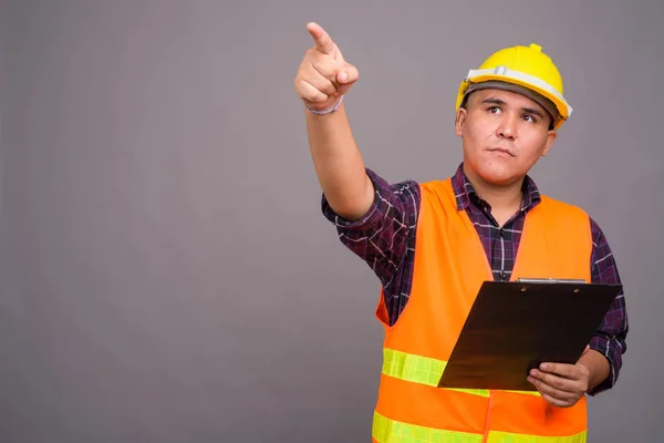 Joven asiático hombre construcción trabajador contra gris fondo —  Fotos de Stock