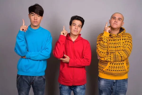 三名年轻的亚洲男子穿着暖和的衣服对抗灰色的背板 — 图库照片