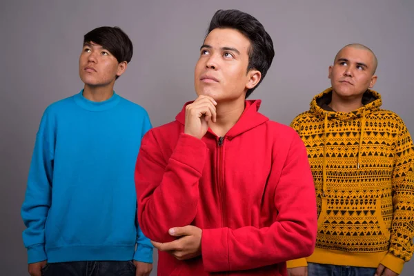Три азіатських юнаки носити теплий одяг проти сірих backgro — стокове фото