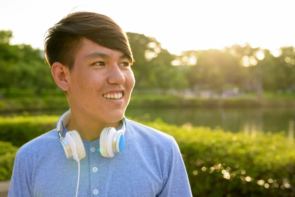 Joven adolescente asiático usando auriculares mientras se relaja en el —  Fotos de Stock
