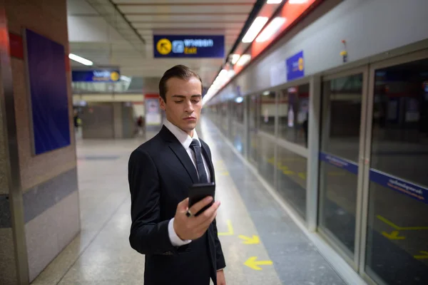 Jeune homme d'affaires utilisant le téléphone à la gare — Photo