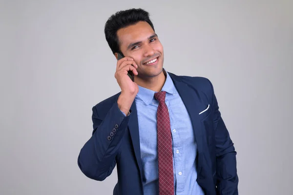 Happy young handsome Indian businessman talking on the phone — Stock Photo, Image
