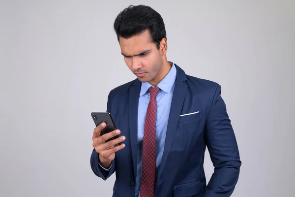 Portrait of young handsome Indian businessman using phone — Stock Photo, Image