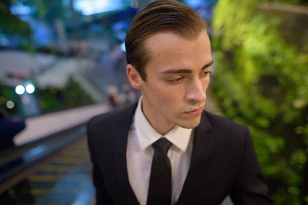 Young businessman standing at escalator while thinking — Stock Photo, Image