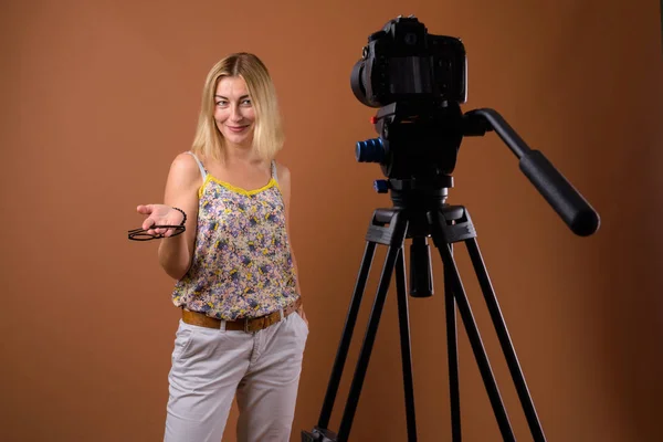 Femme photographe avec appareil photo reflex numérique en trépied au studio — Photo