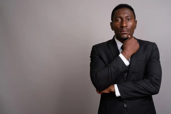 Young handsome African businessman against gray background — Stock Photo, Image