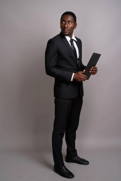 Mladý pohledný africký podnikatel proti šedé pozadí — Stock fotografie