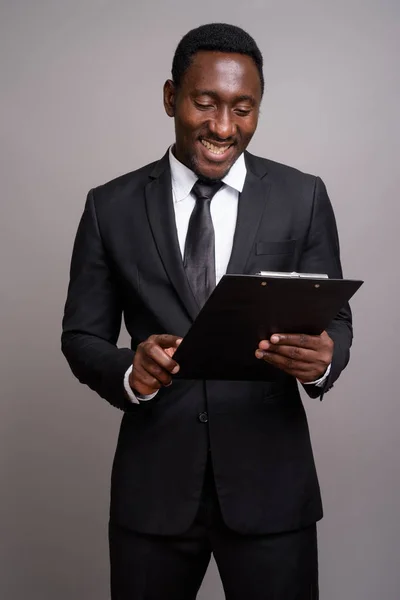 Fiatal jóképű afrikai üzletember szürke háttérrel — Stock Fotó