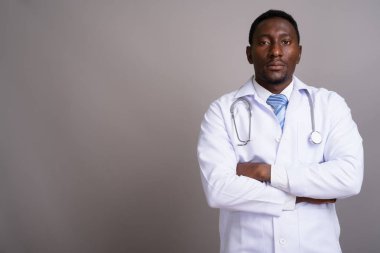 Gri arka planda genç yakışıklı Afrikalı doktor