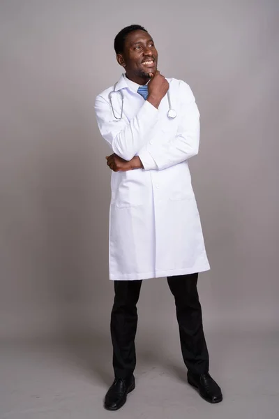 Молодой красивый африканский врач на сером фоне — стоковое фото