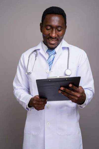 Young handsome African man doctor against gray background — Stock Photo, Image