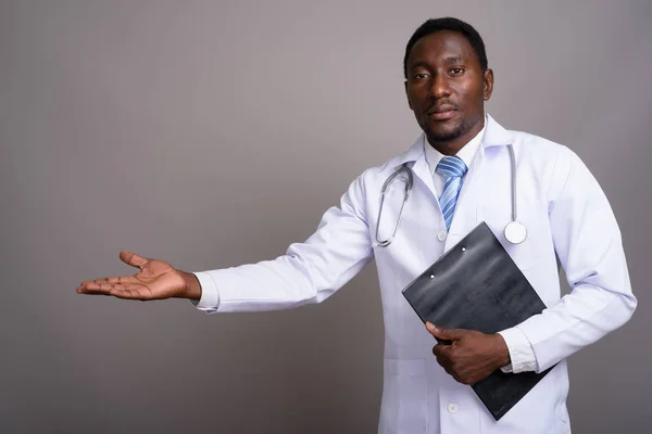 Young handsome African man doctor against gray background — Stock Photo, Image