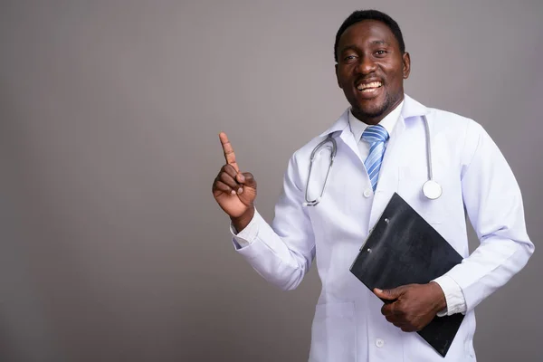Young handsome African man doctor against gray background — Stock Photo, Image