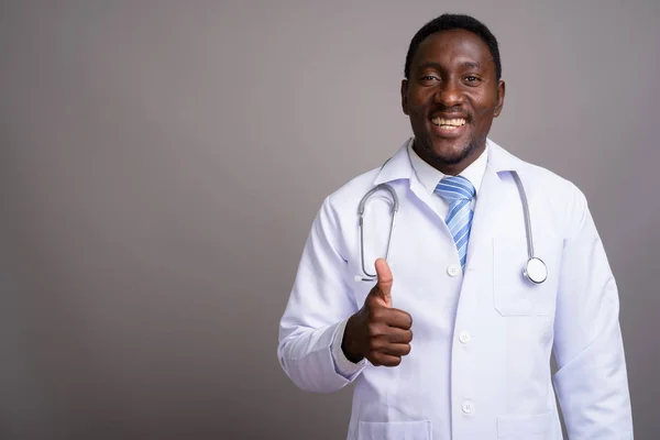 Young handsome African man doctor against gray background — Stock Photo, Image